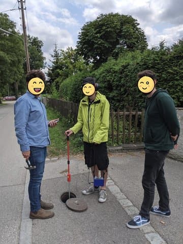 Team performing acoustic leak detection around a manhole cover